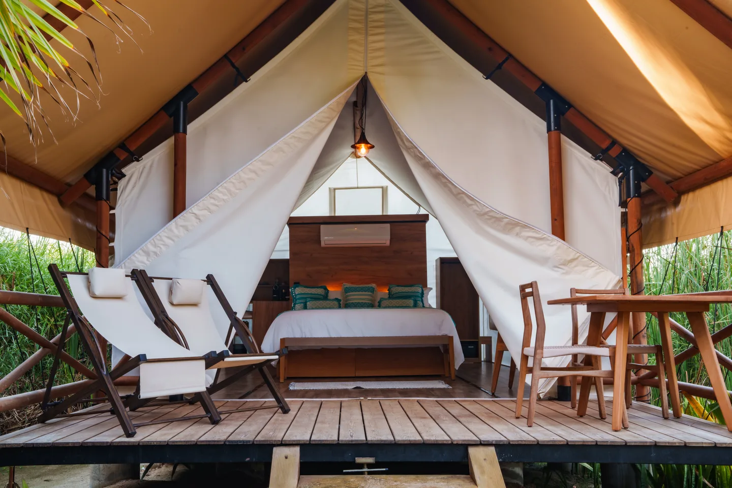 Aqua Tent seen from the front, its canvas drawn back to show the king bed and a deck with lounge chairs at NEST Los Cabos