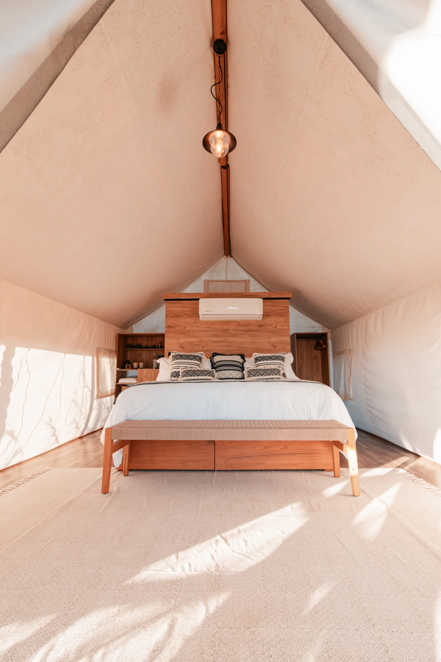 King bed with a timber headboard and air conditioning under the peaked canvas roof of an Aqua Tent at NEST Los Cabos