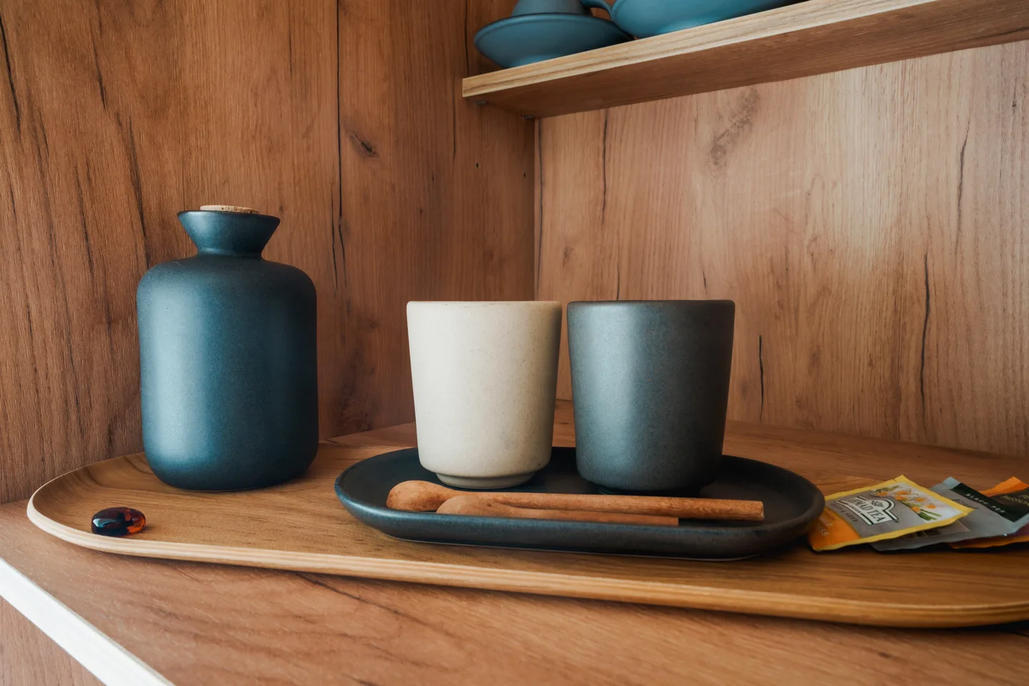Tea tray with a ceramic carafe and two cups on a timber shelf at NEST Los Cabos