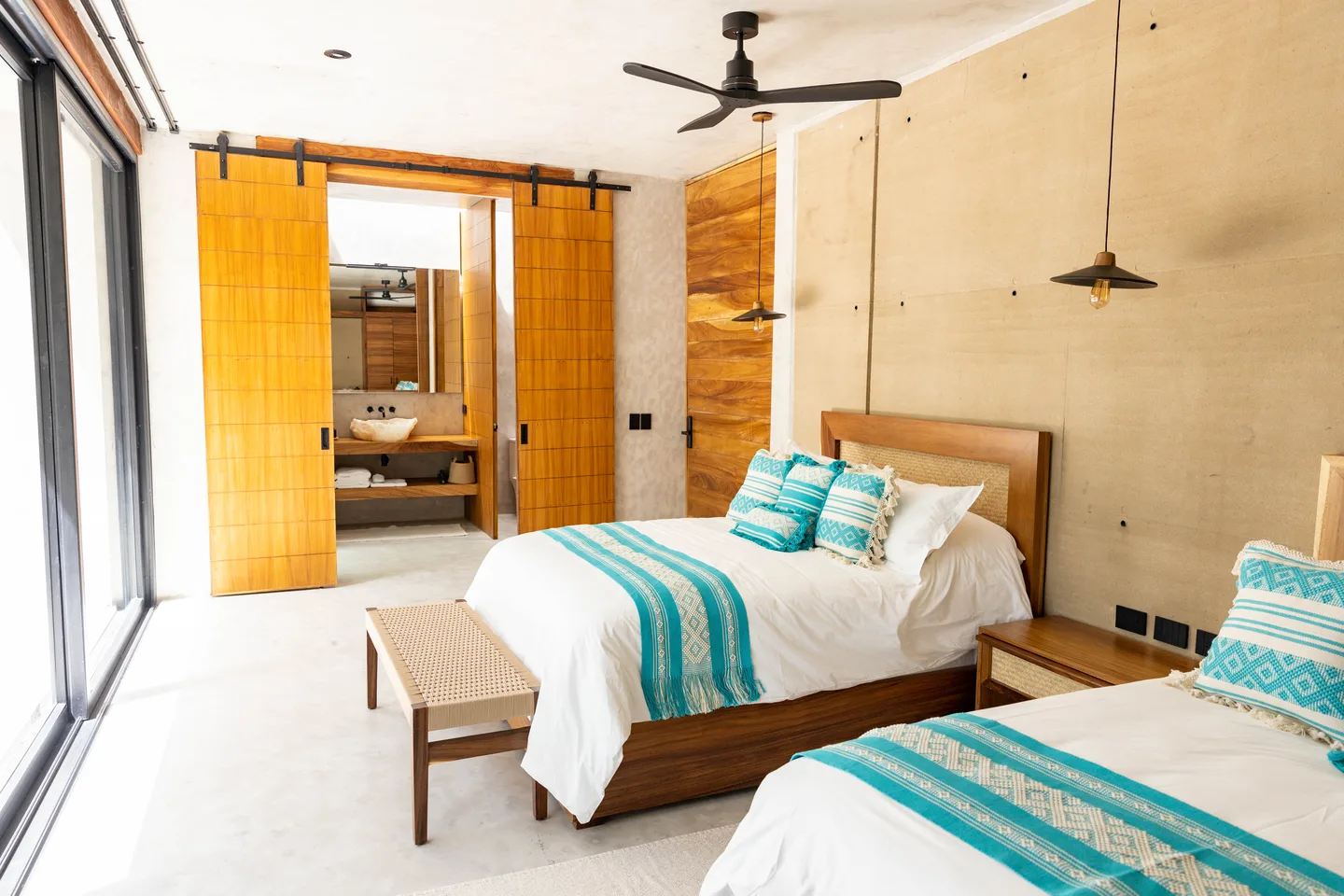 Two queen beds in the Terra Double Room with sliding timber doors open to the bathroom at NEST Los Cabos